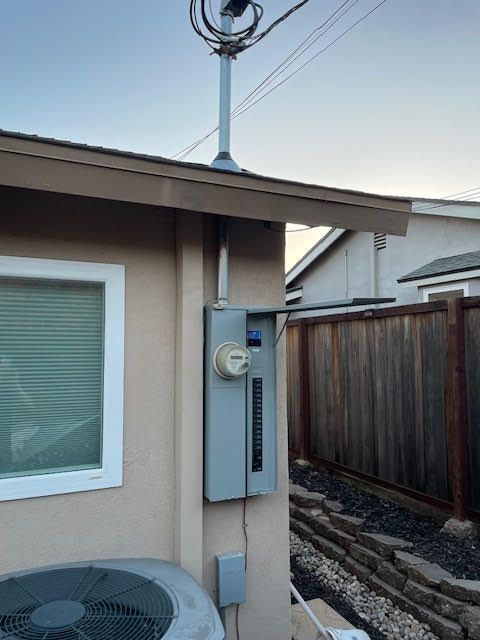 Electric meter on an exterior wall of a building; conduit and wires visible.