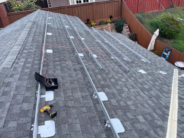 Solar panel installation on a rooftop with mounting hardware and electrical components visible.