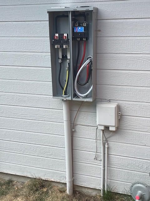 Electrical meter box mounted on a white house siding with conduit and connected wiring.