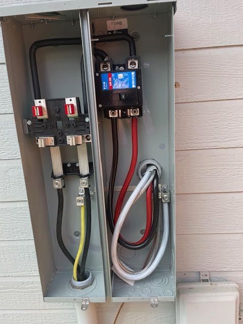 Open electrical panel with wires and circuit breakers. Gray metal box, wires in black, red, white, yellow.
