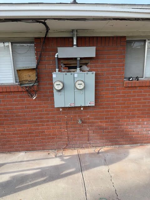 Electrical meters on a brick building exterior. Three gray meter boxes and conduit are visible.