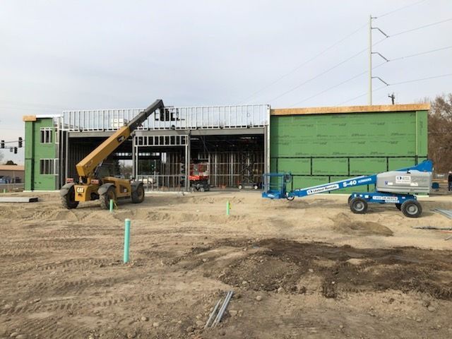 Construction site: building framework with machines and green insulation.