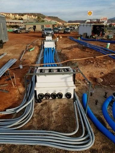 Construction site with conduit pipes, boxes, and a Shell gas station in the background.