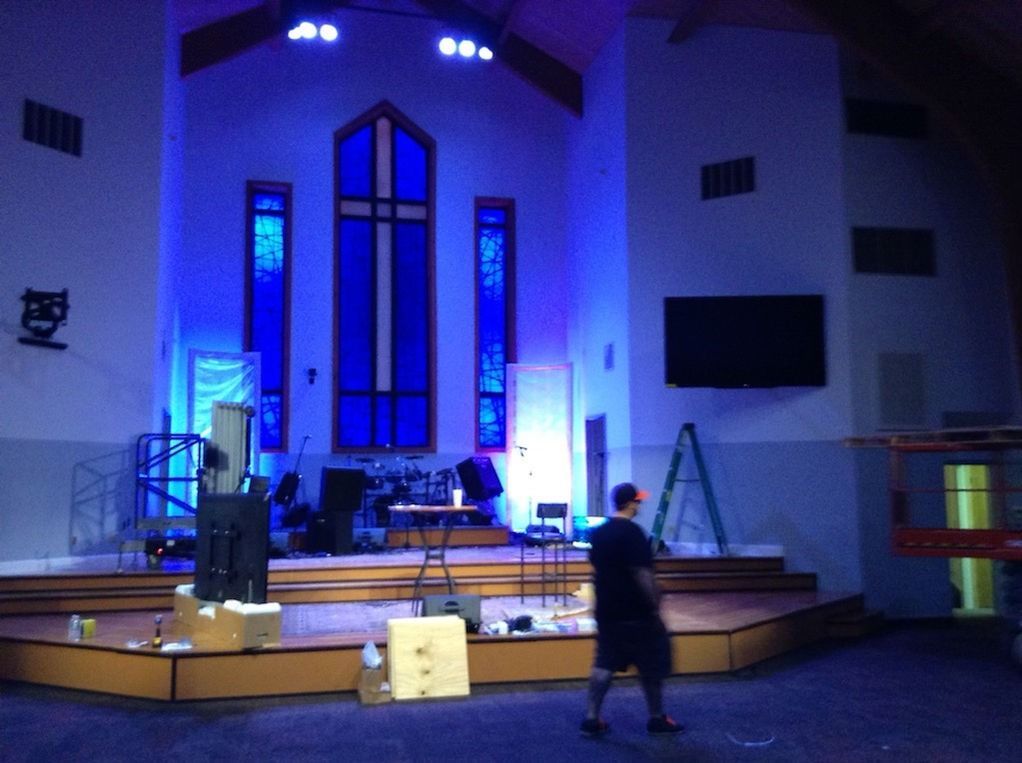 Church stage with blue lighting; person standing on floor.