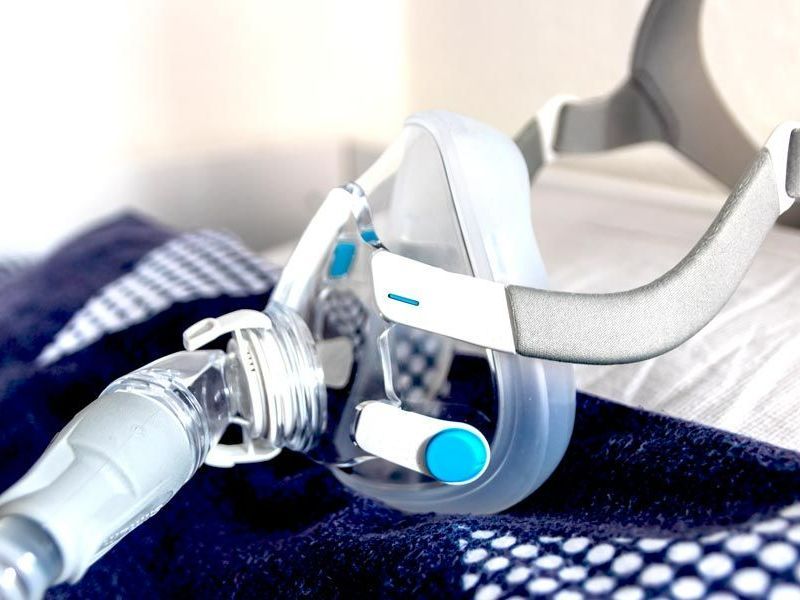 A close up of a cpap mask on a bed.