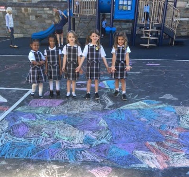 A group of young girls standing in front of a playground