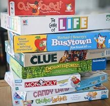 A stack of board games sitting on top of each other on a wooden table.