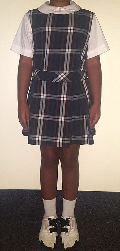 A girl is wearing a plaid dress and white socks