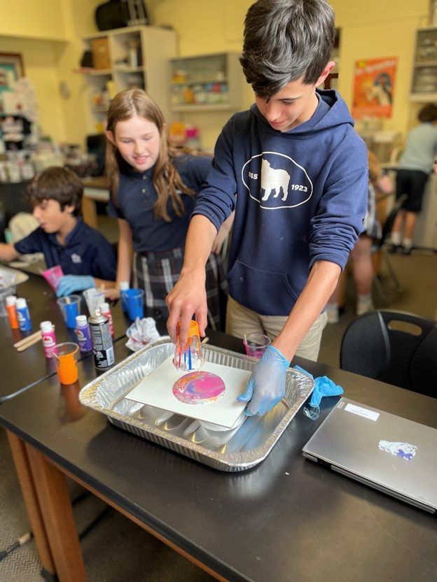 A boy in a blue hoodie is painting a picture