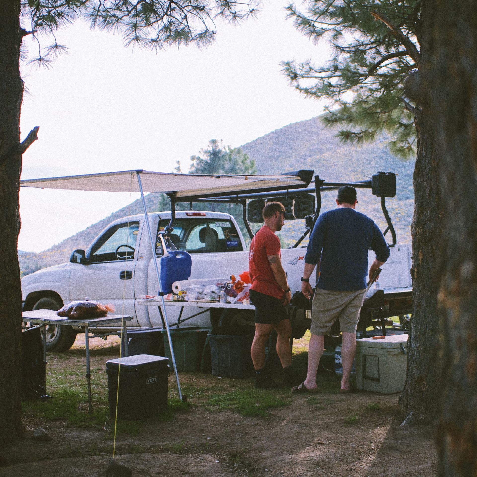A man in a red shirt is standing in front of a white truck