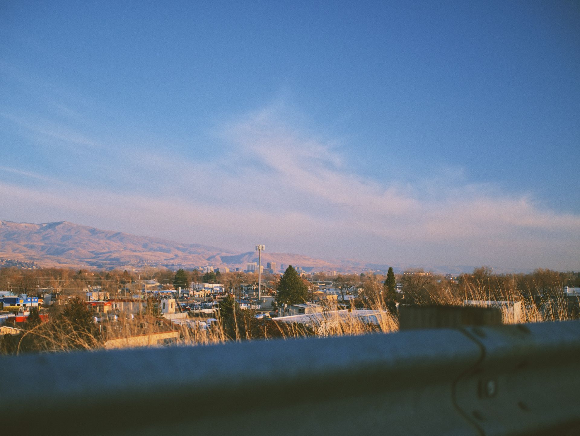 A view of a city from a highway with mountains in the background.