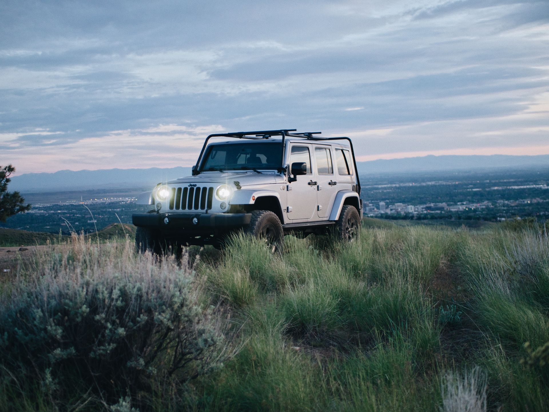A white jeep is parked on top of a grassy hill.
