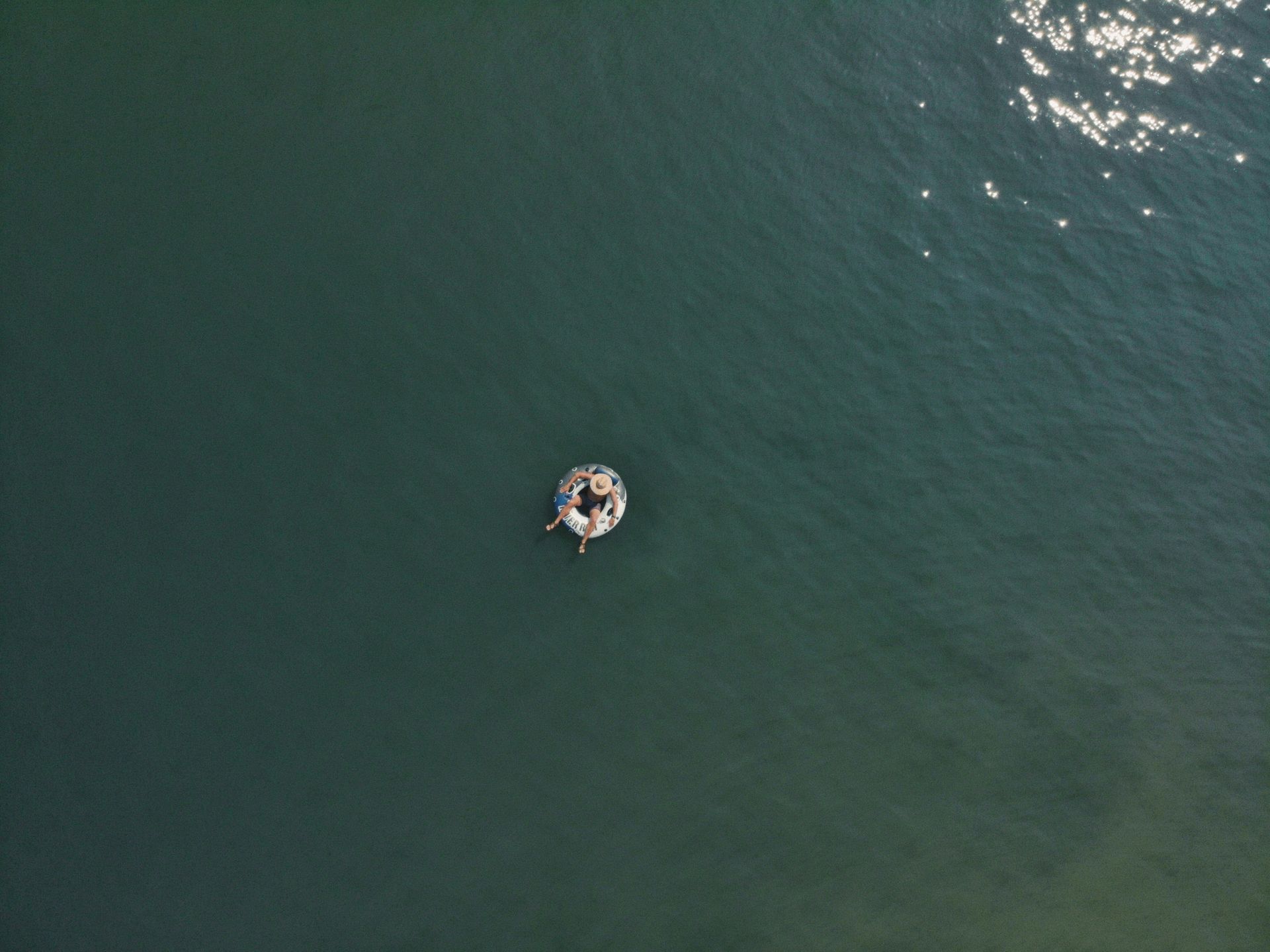 An aerial view of a person floating on a raft in the ocean.