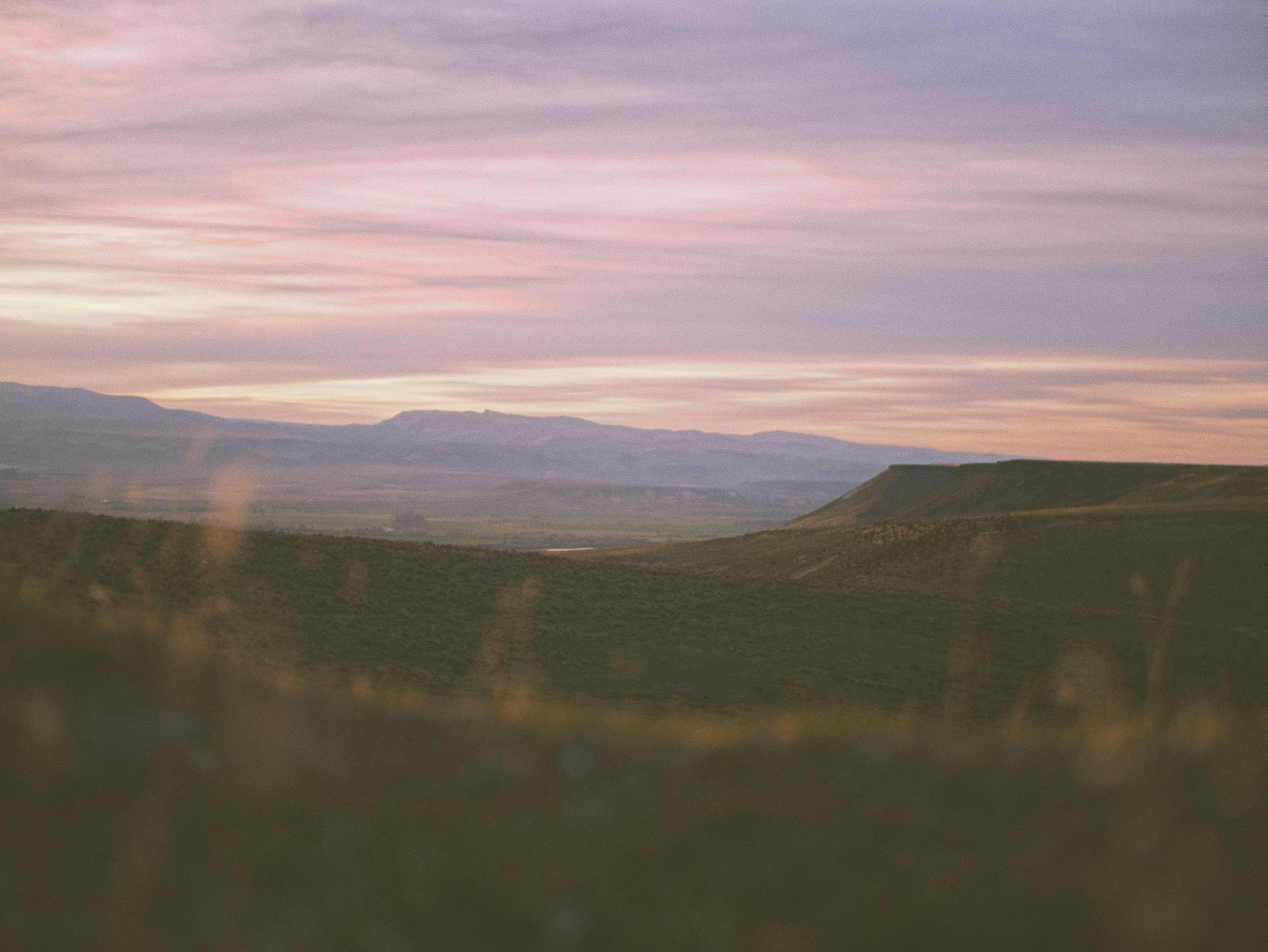 A sunset over a valley with mountains in the background