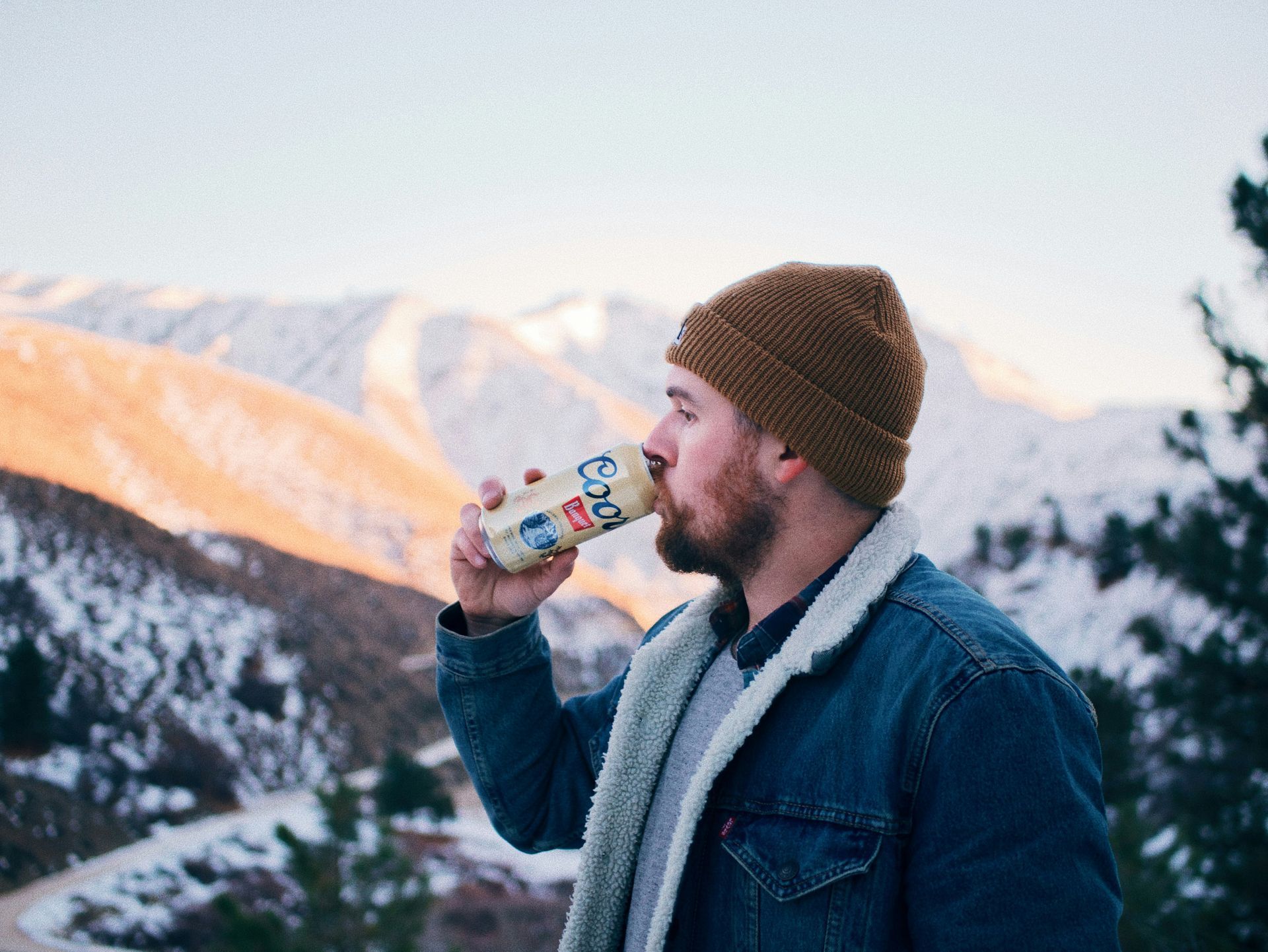 A man is drinking from a bottle in the mountains.