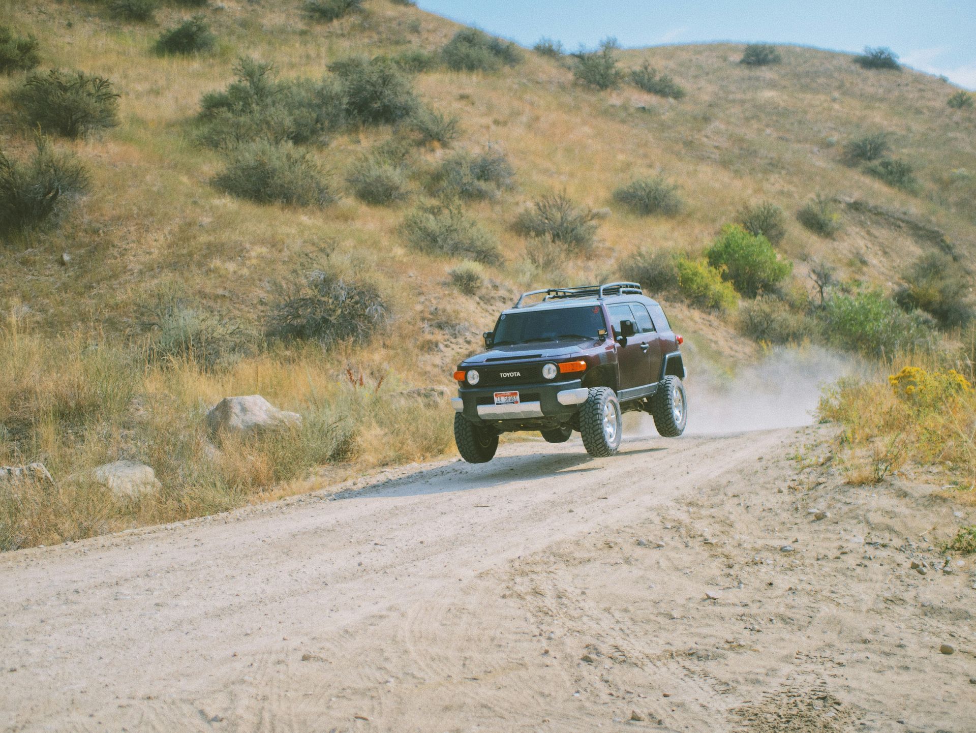 A black suv is driving down a dirt road.