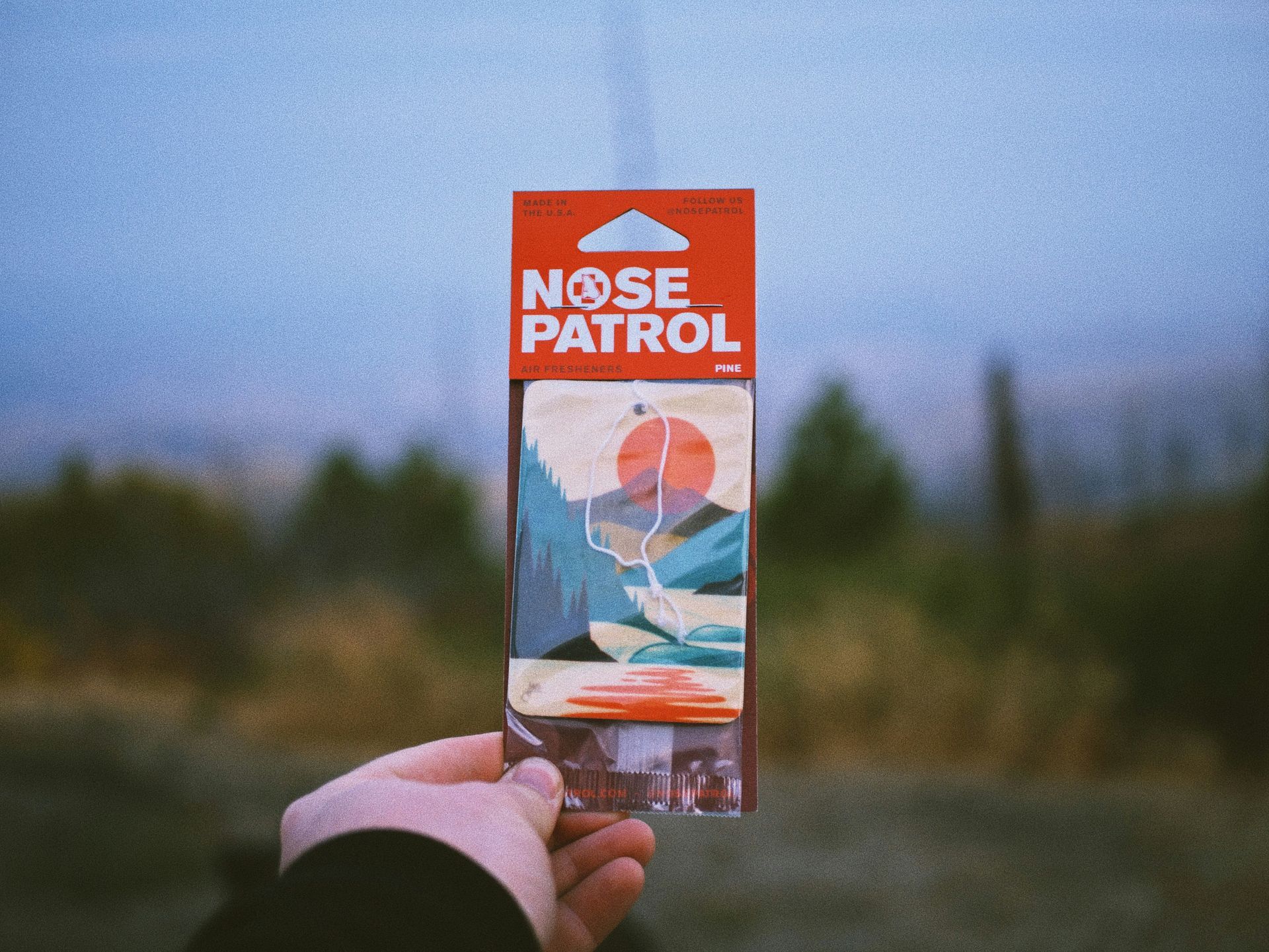 A person is holding a nose patrol air freshener in their hand.