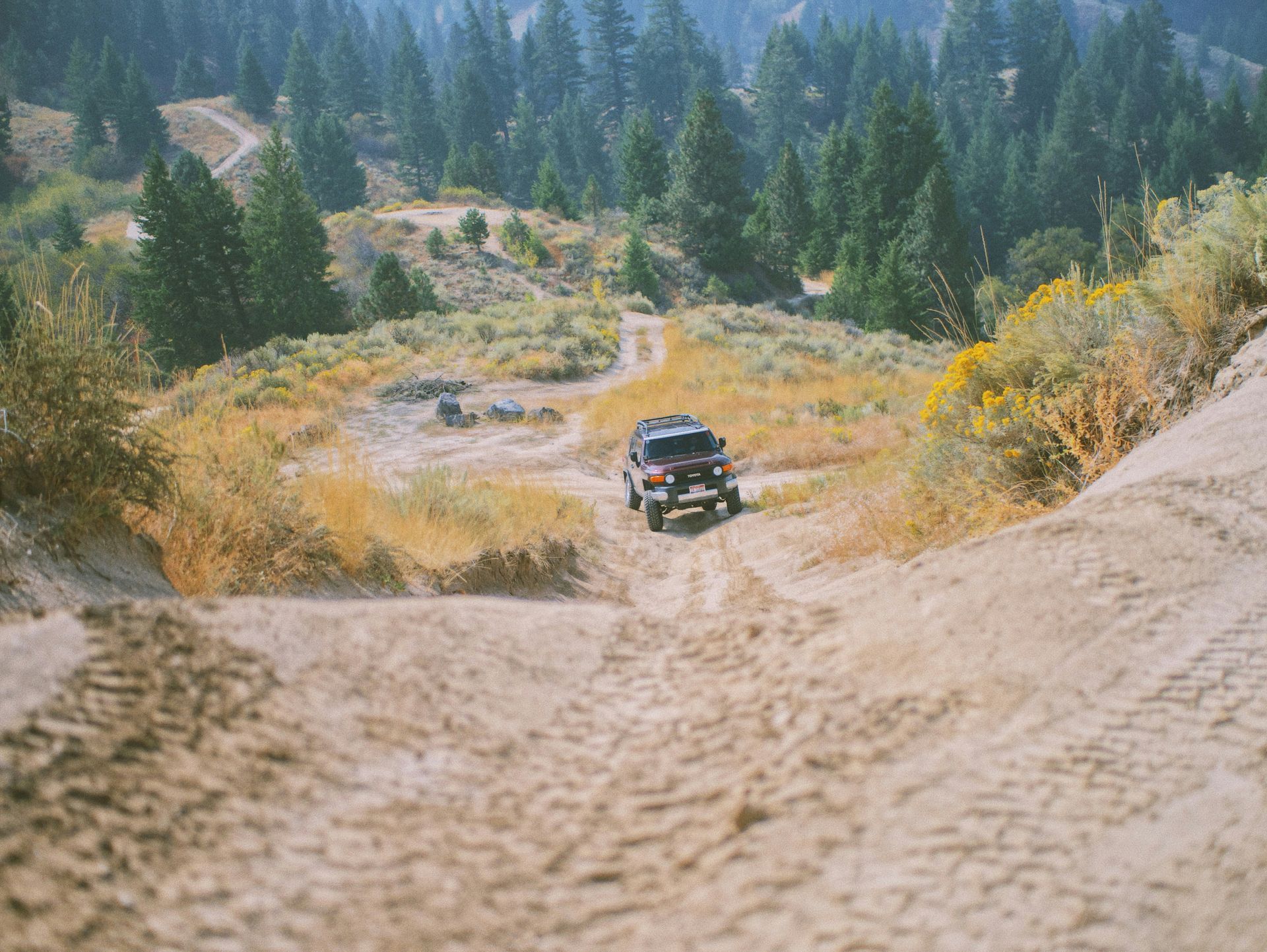 A jeep is driving down a dirt road in the mountains.