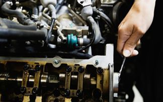 Una persona está trabajando en el motor de un automóvil con una llave.