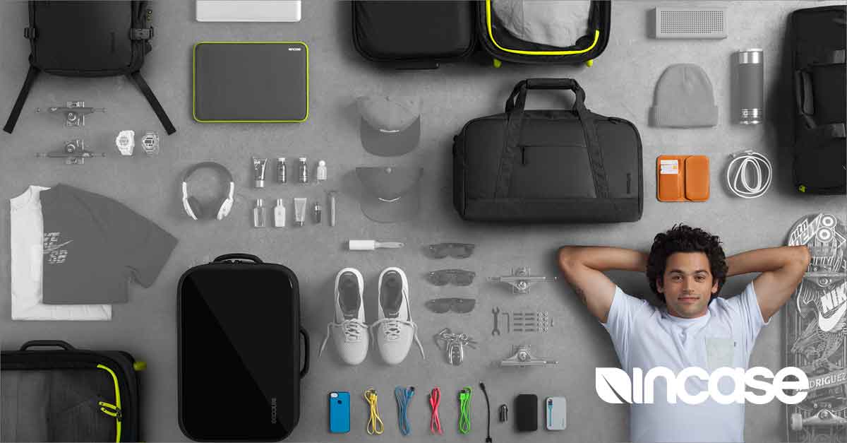 A man is laying on a concrete surface surrounded by luggage and other items.