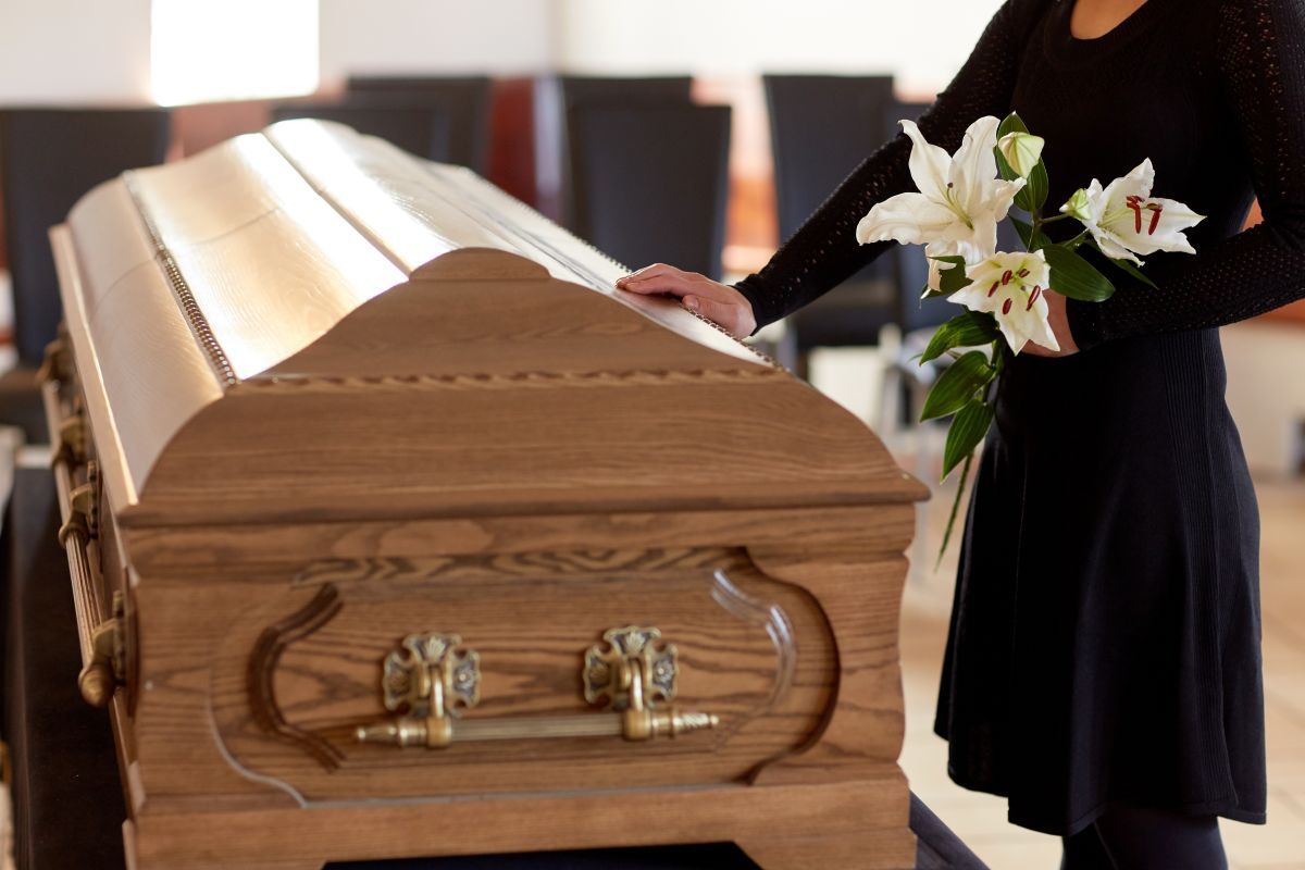 A group of people are standing around a coffin at a funeral.