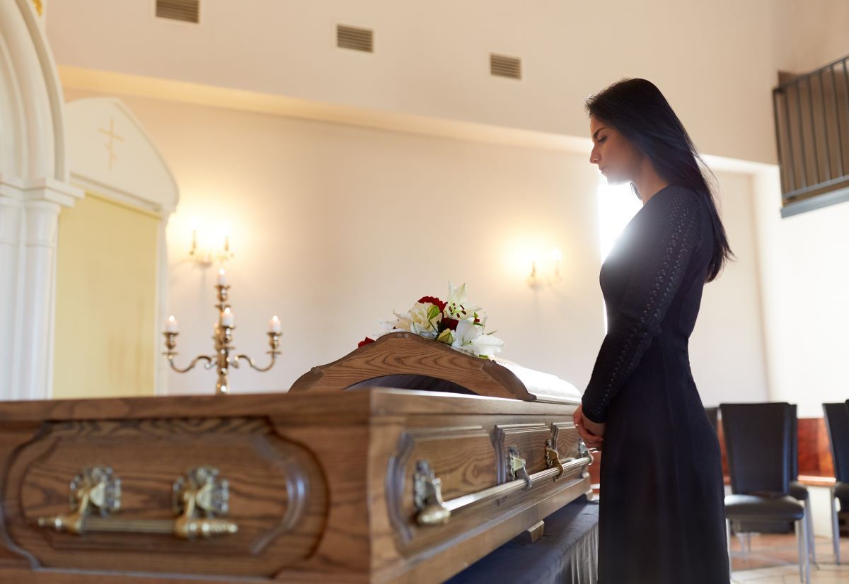 A group of people are standing around a coffin at a funeral.