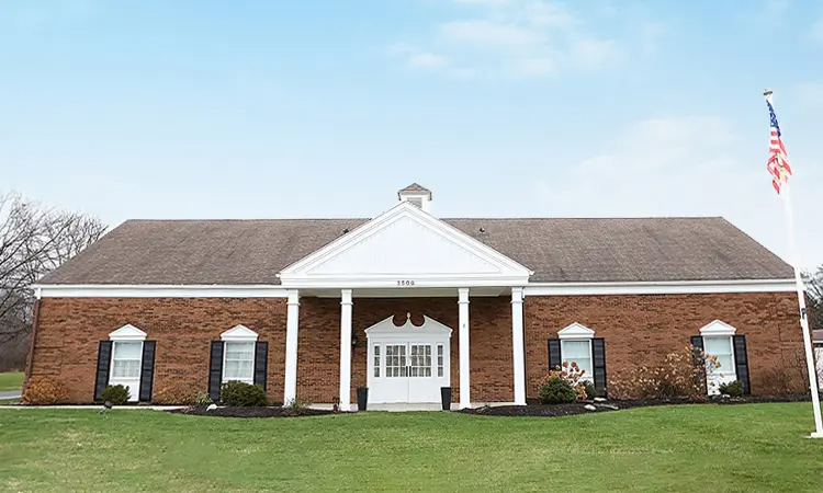 A large white building with a brown roof and a lot of windows.