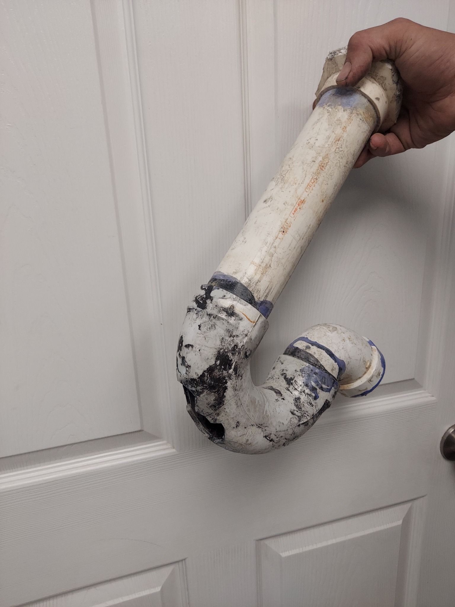 A person is holding a pipe in their hand in front of a door.