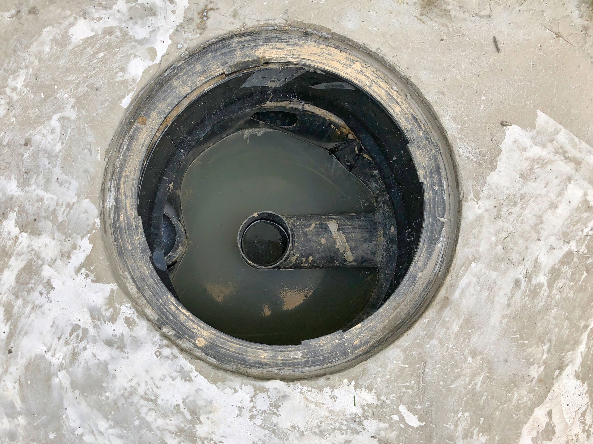 A manhole cover with a hole in the middle of it filled with water.
