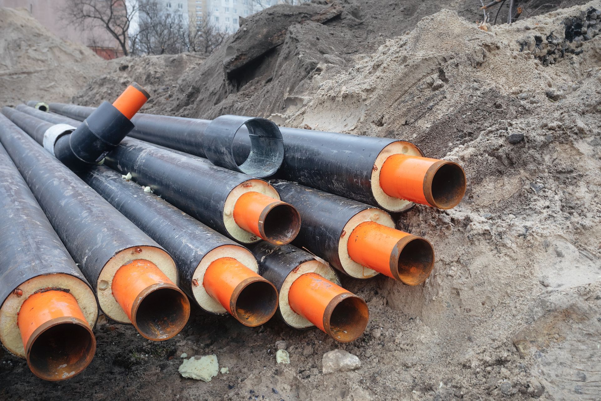 A bunch of pipes are stacked on top of each other in the dirt.