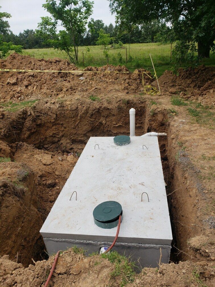 A large concrete septic tank is sitting in the middle of a dirt field.