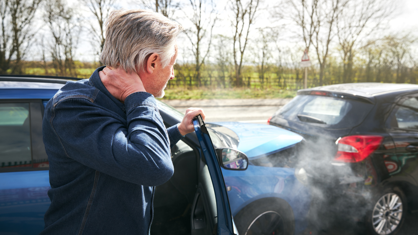 A man is holding his neck after a car accident.