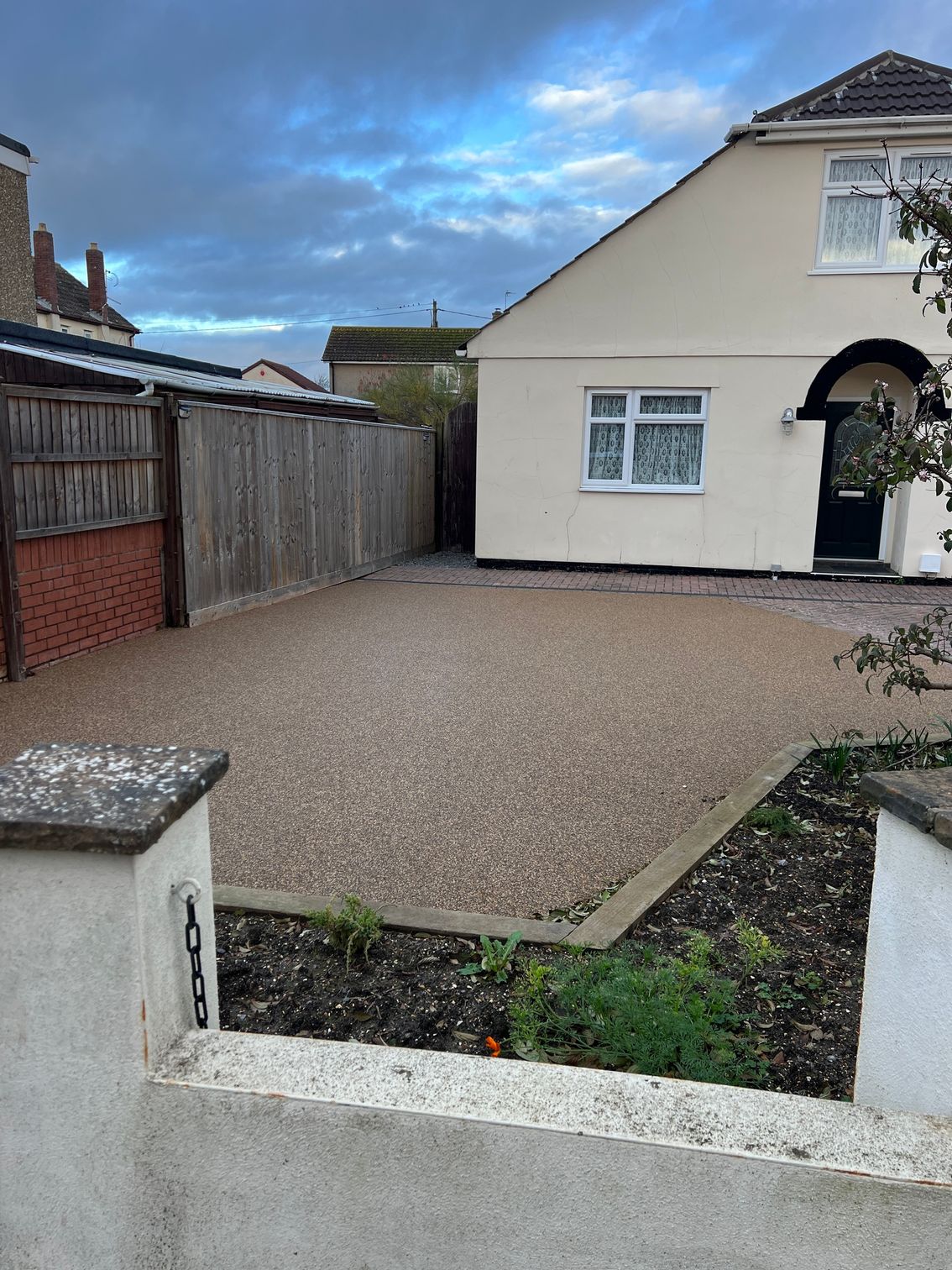 Beige resin driveway outside a cream two-story home.