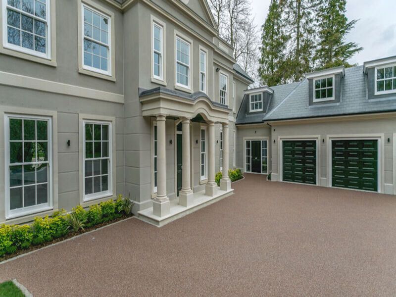 Resin driveway in front of a grand cream house with lots of windows.