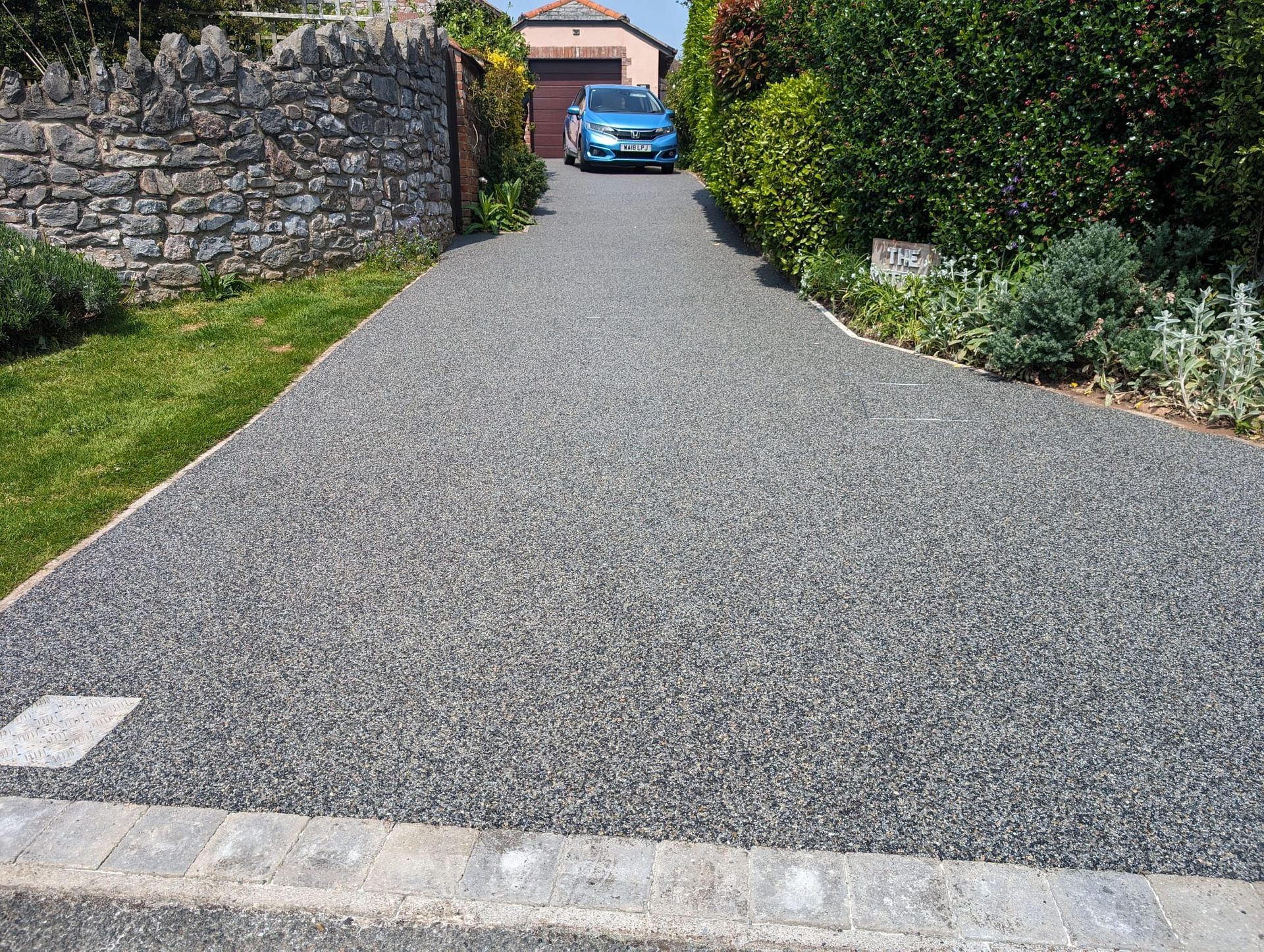 Grey resin bound driveway with a light grey block border.