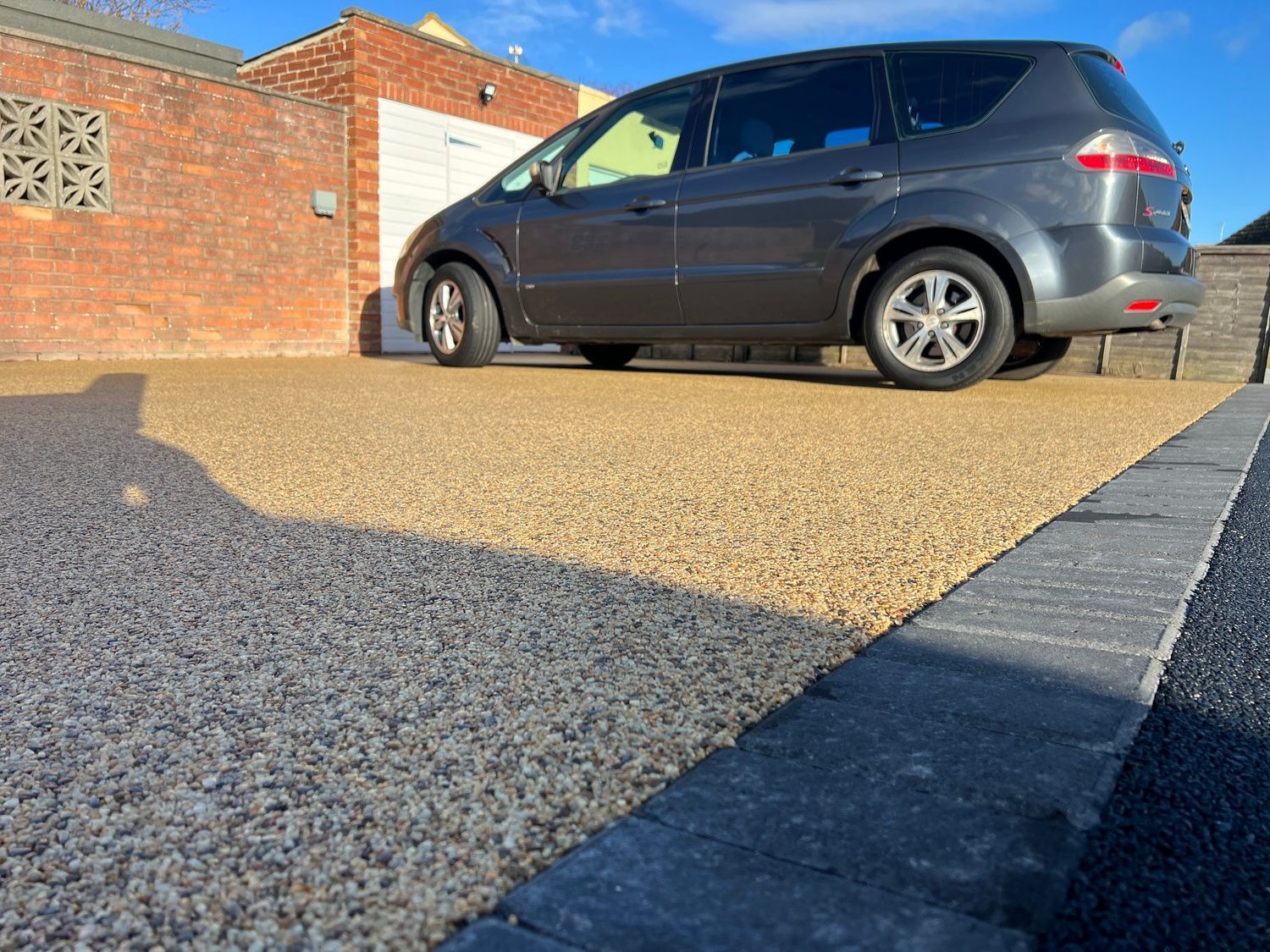 A resin driveway with a car parked on top of it.