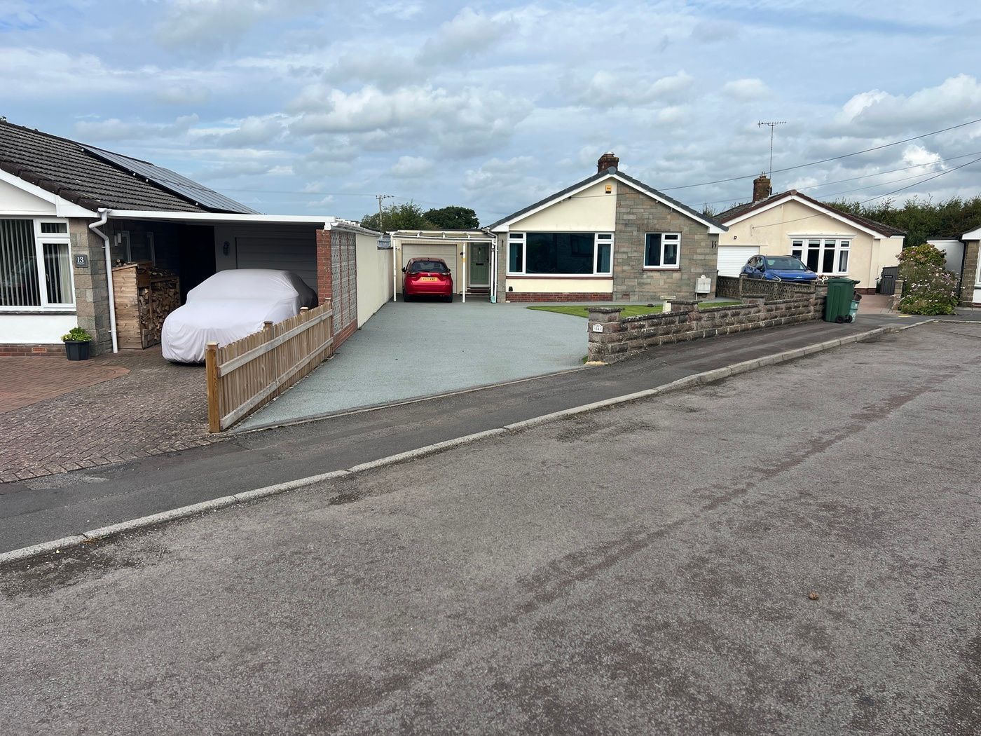 Grey resin driveway with a red car parked on it.
