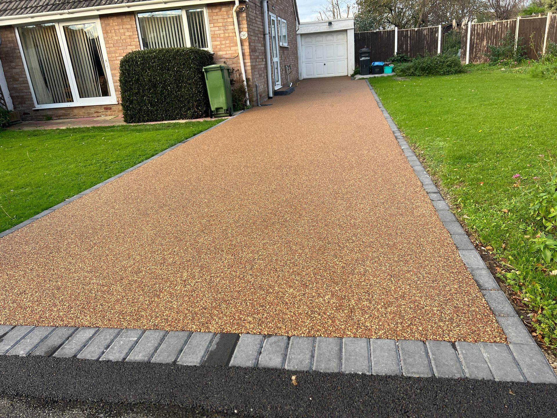 A driveway with gravel and bricks leading to a house.