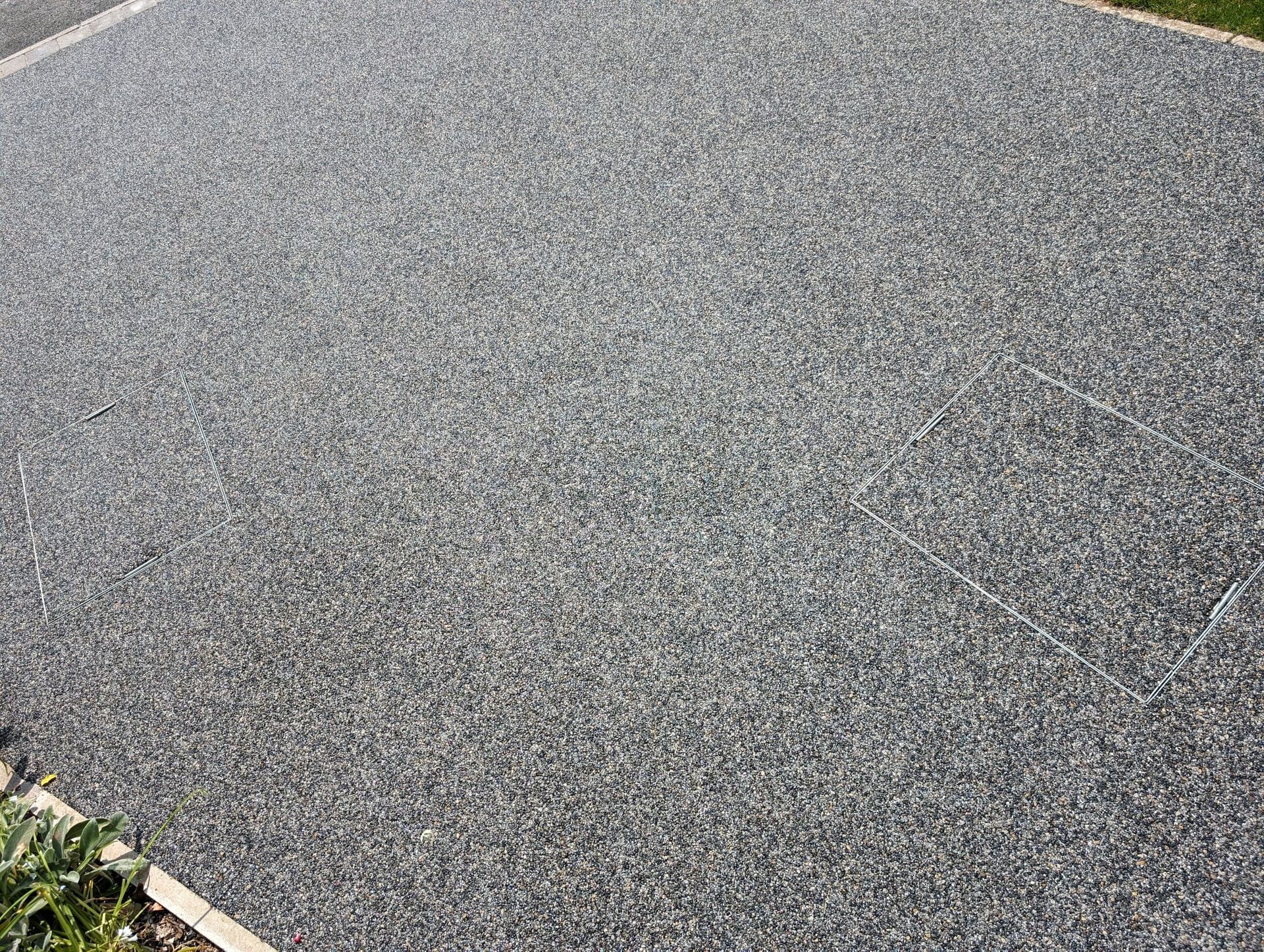 A close up of a gravel driveway with grass in the background.