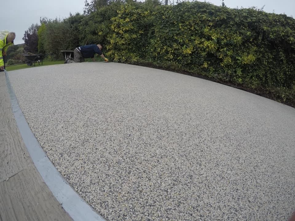 A person is laying on a concrete surface in a park.