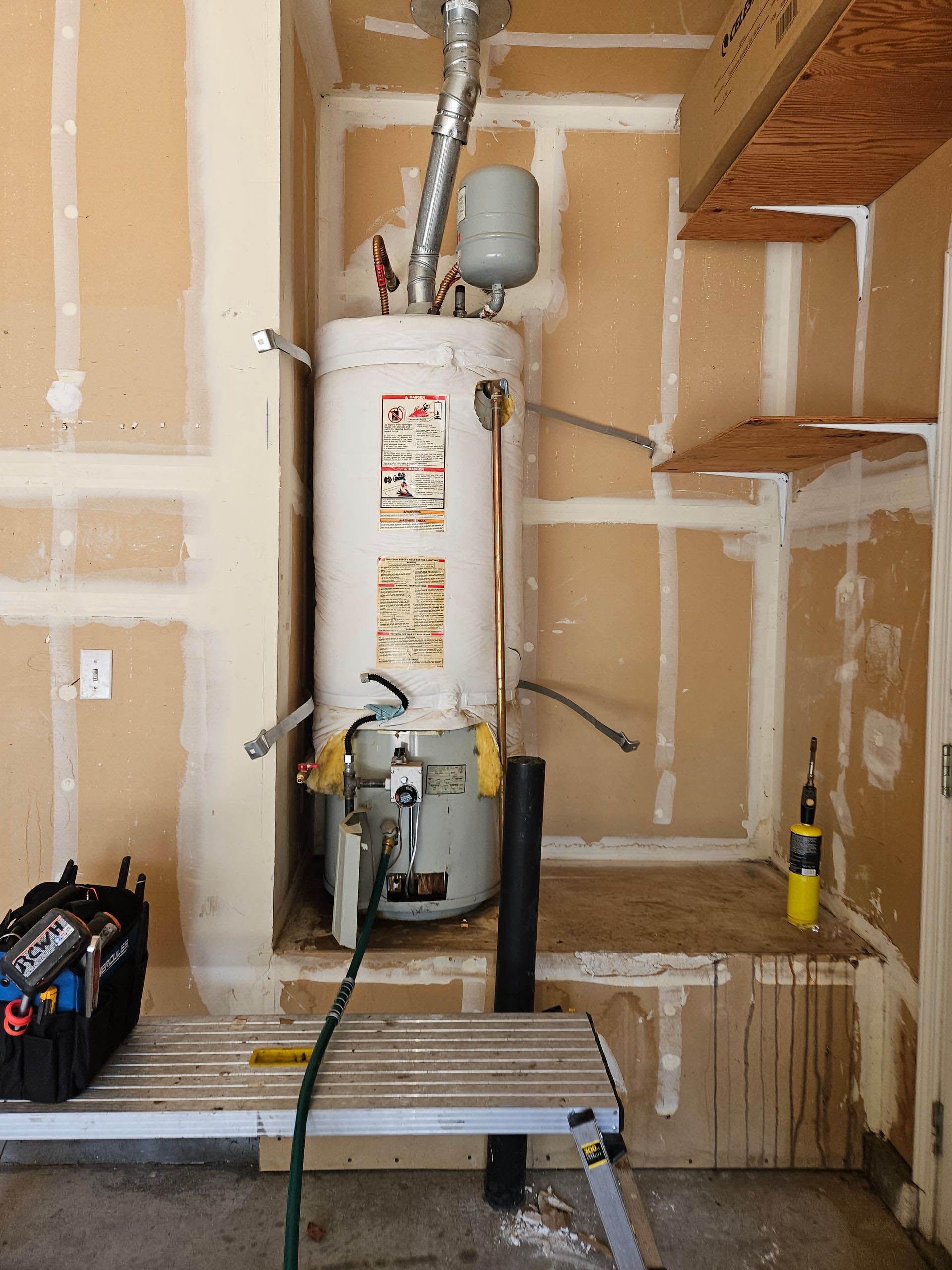 A water heater is sitting in a corner of a room