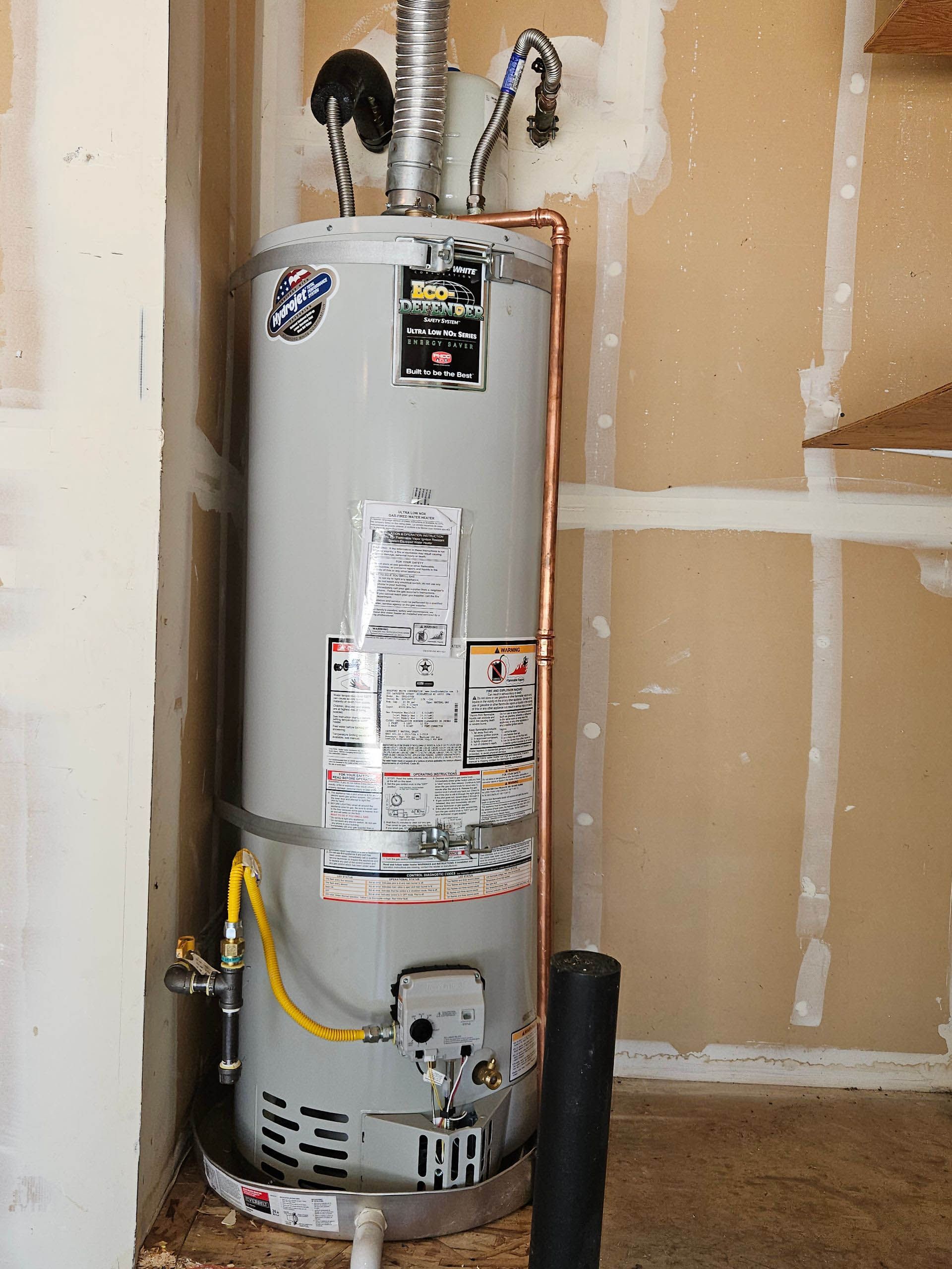 A water heater is sitting in a room next to a wall.