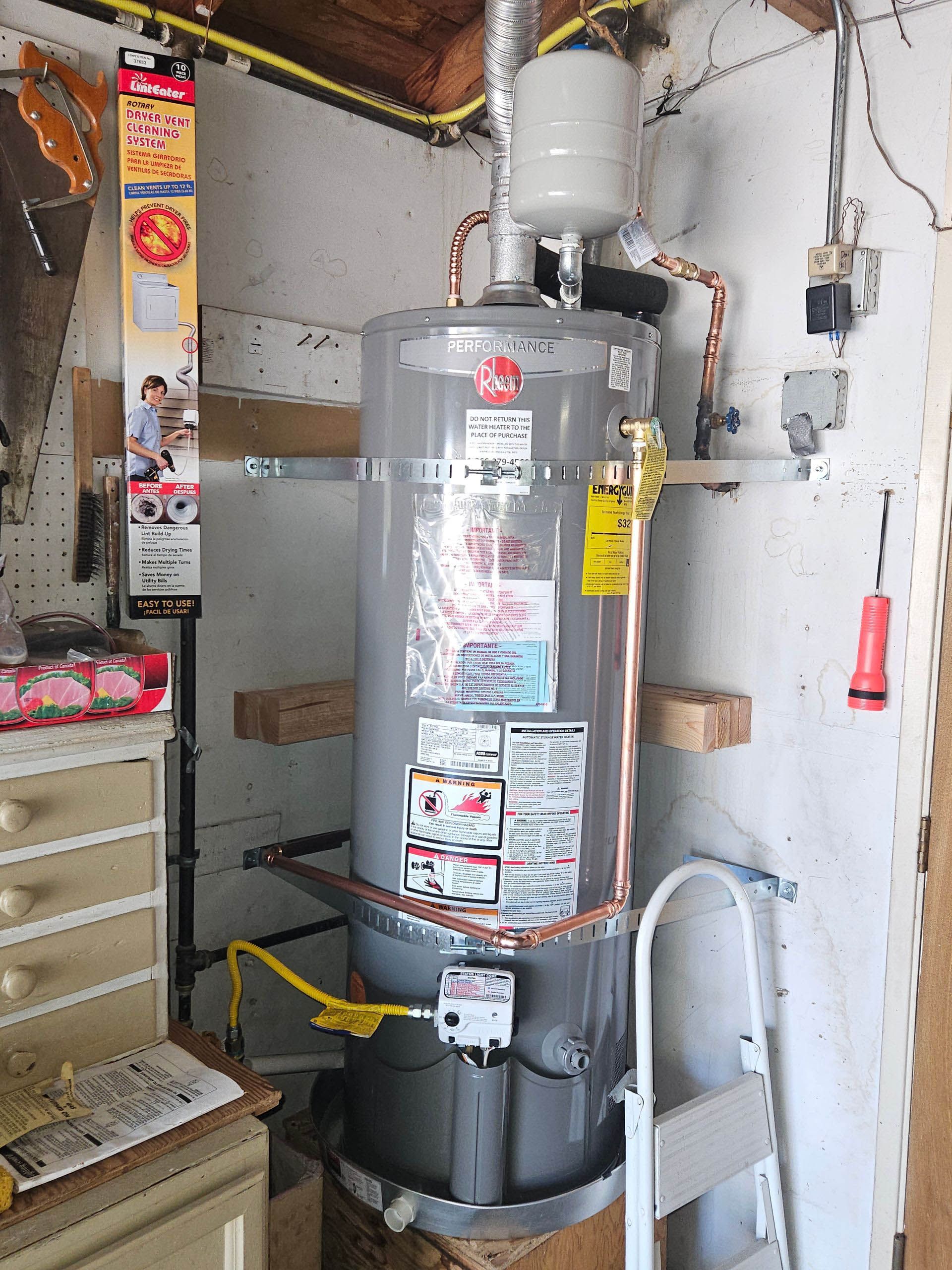 A water heater is sitting in a room next to a ladder.