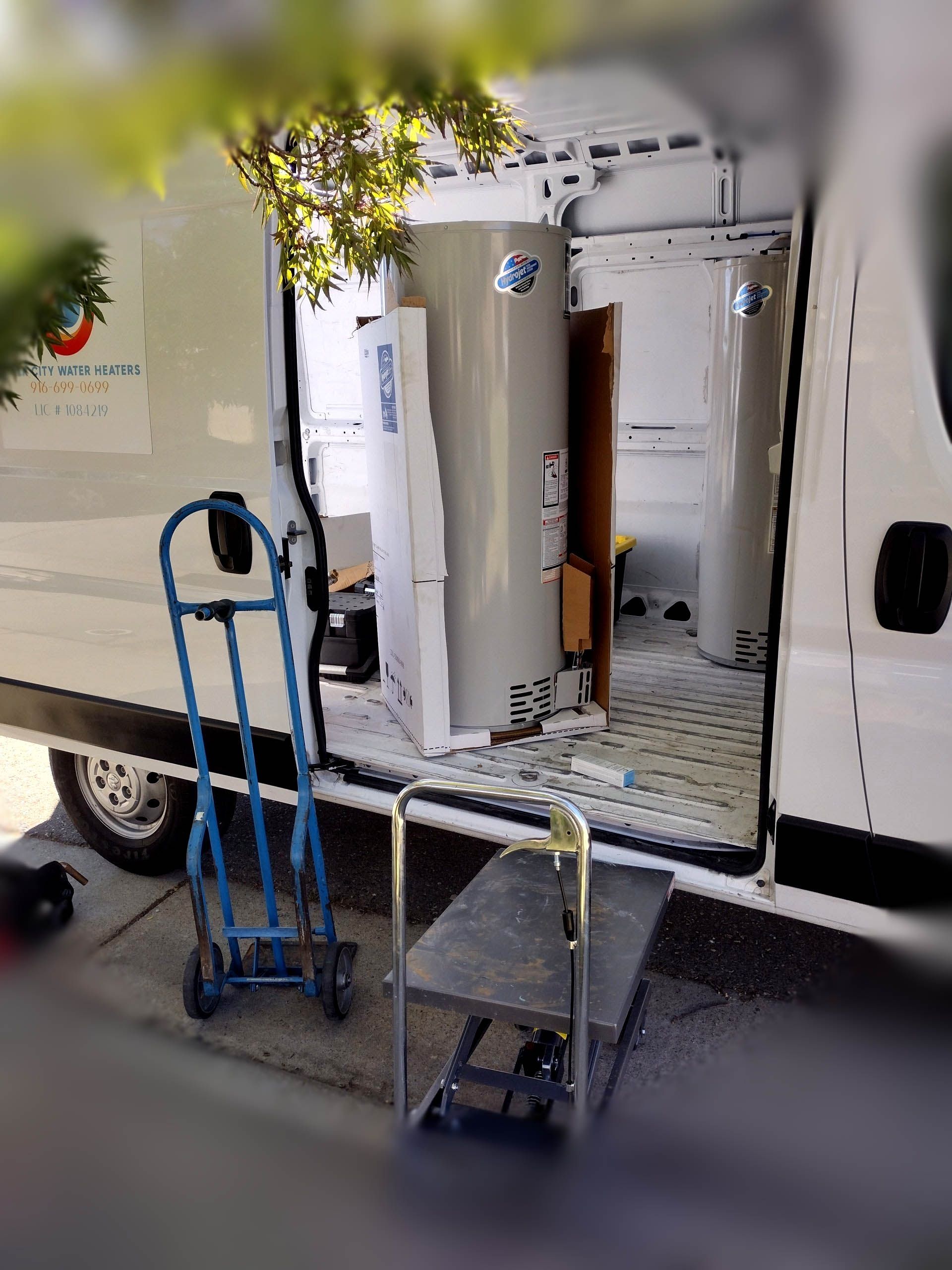 A white van with a water heater in the back is parked on the side of the road.