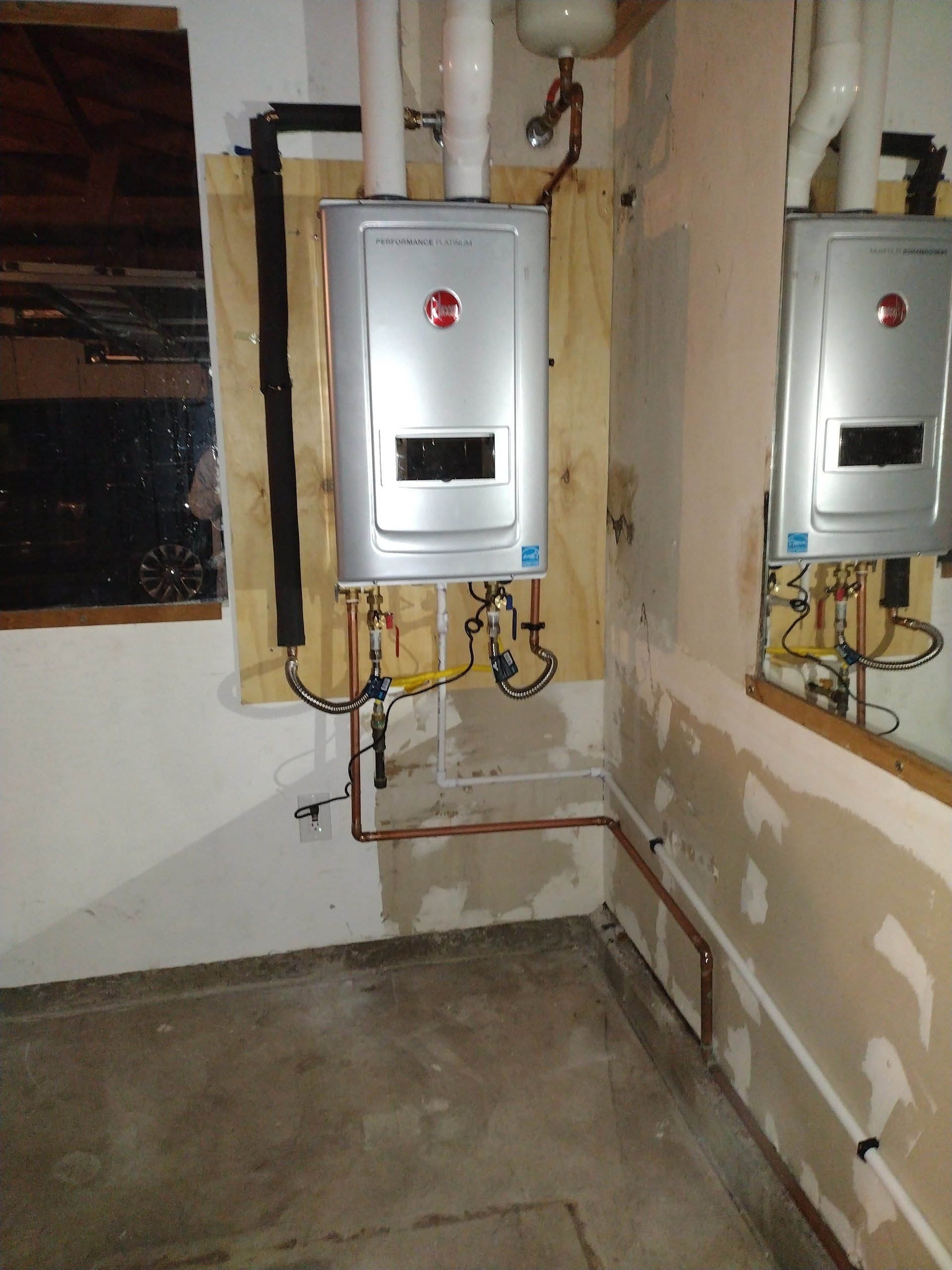 Two water heaters are mounted to the wall in a room