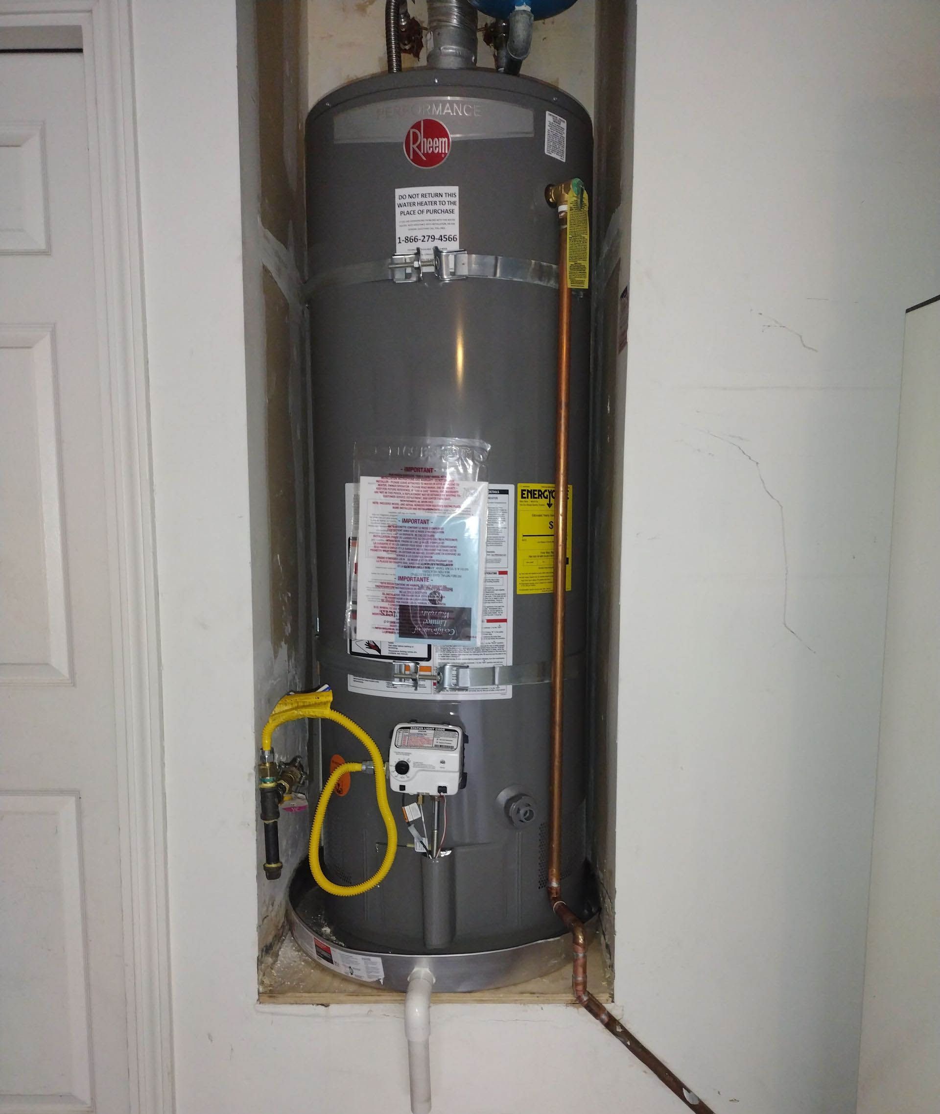 A gray water heater with a yellow hose attached to it