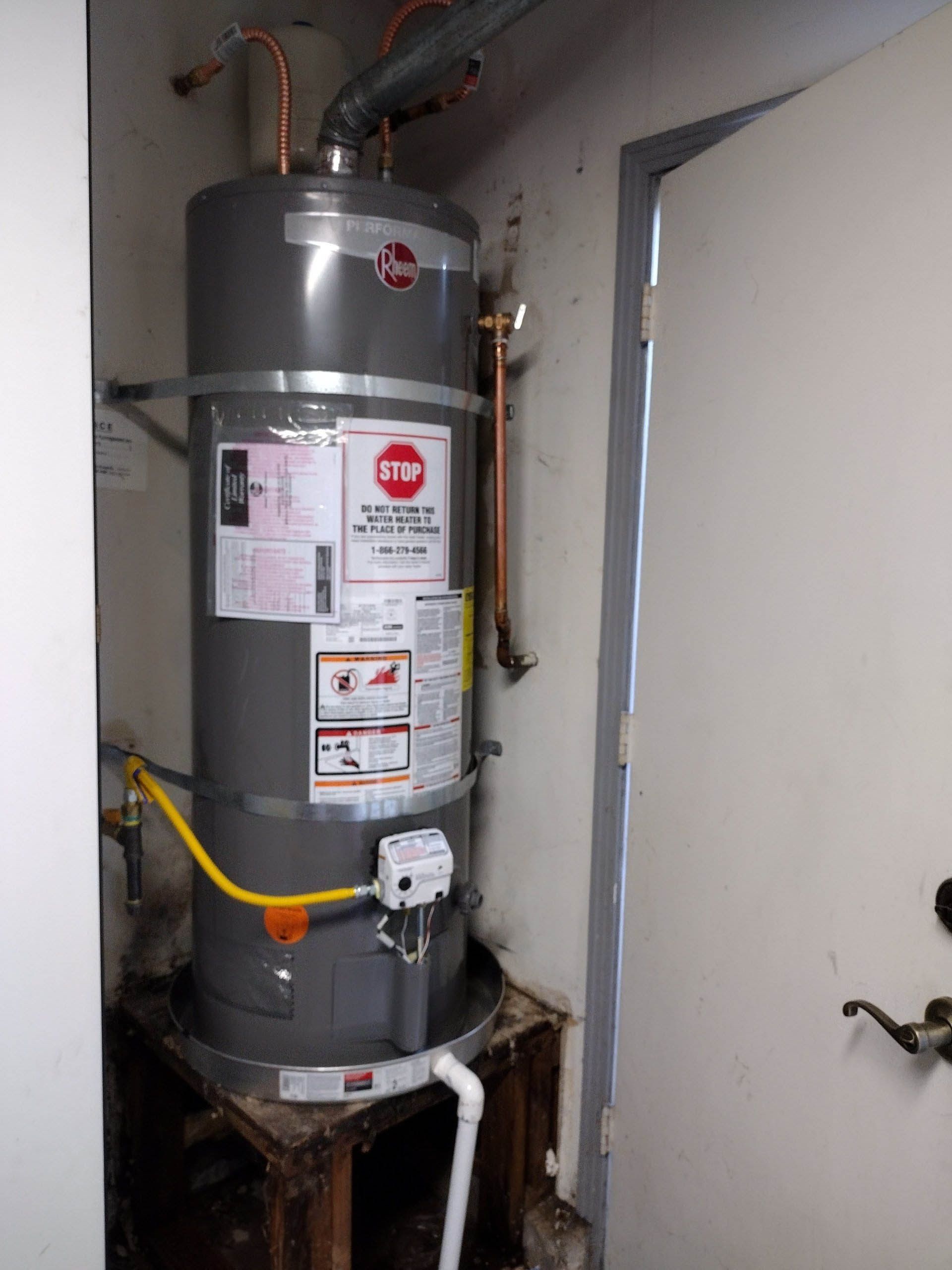 A water heater is sitting in a room next to a door.