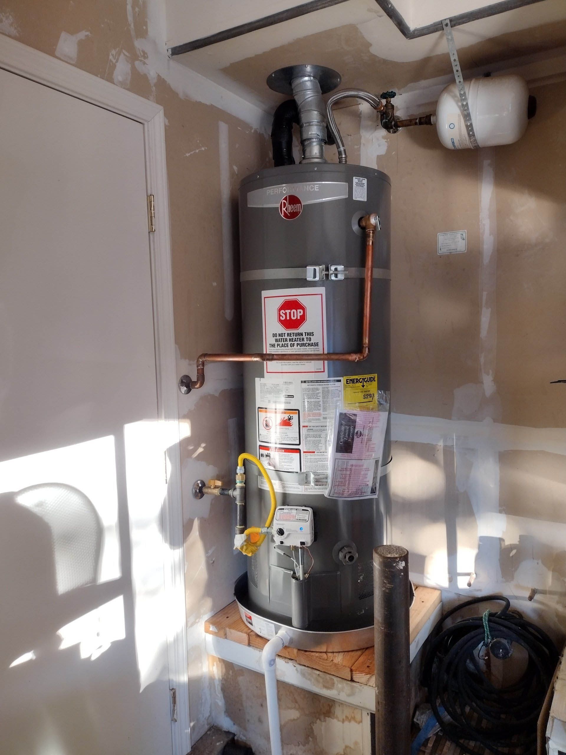 A water heater is sitting in a corner of a room.