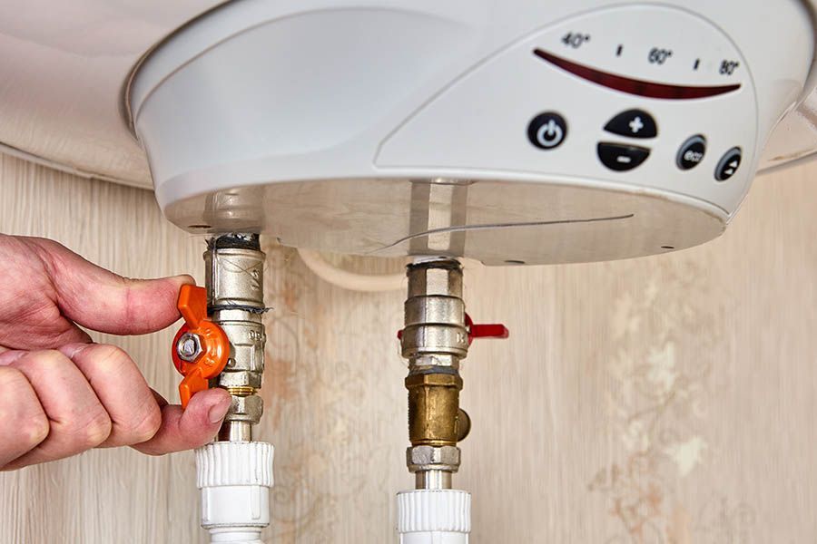 A person is fixing a water heater with a valve.