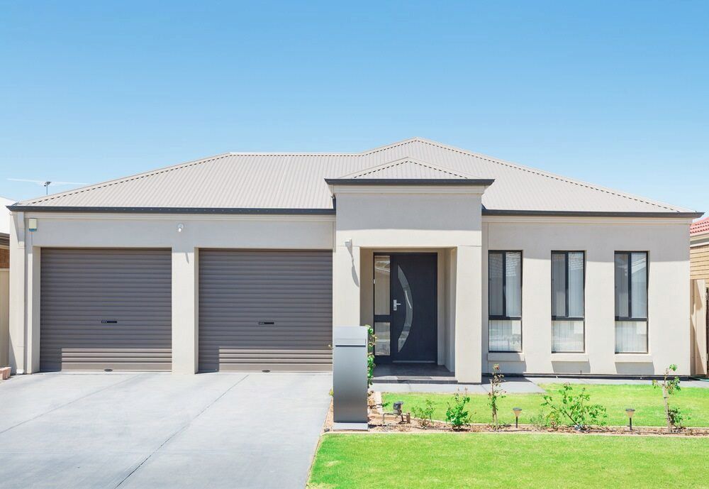 Modern beige house with a two-car garage and dark gray door on a sunny day — Country Coast Valuers in Forster, NSW